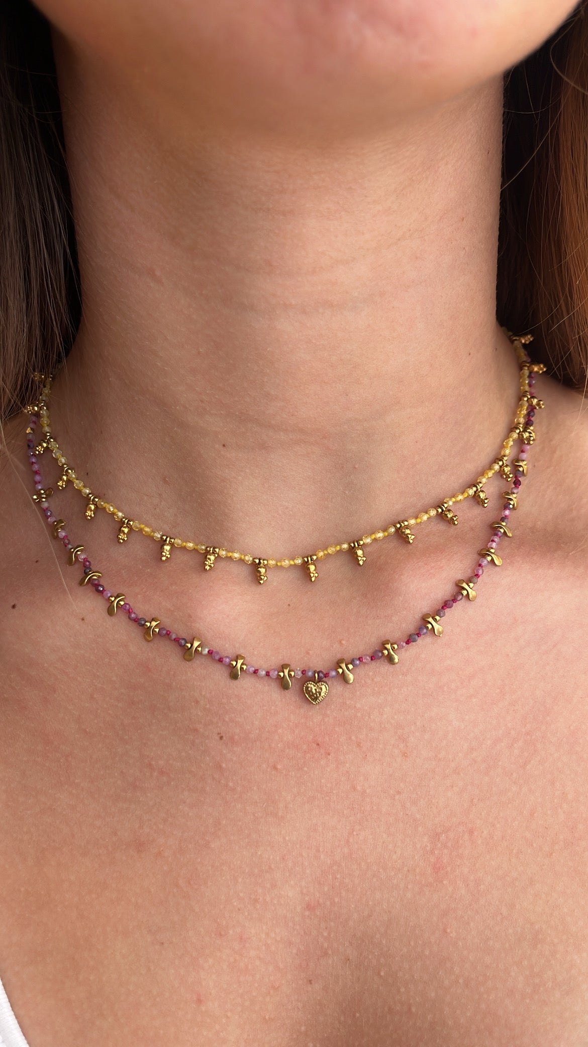 Femme portant deux colliers dont un avec des petites perles jaune, et un autre avec des petites perles rose 