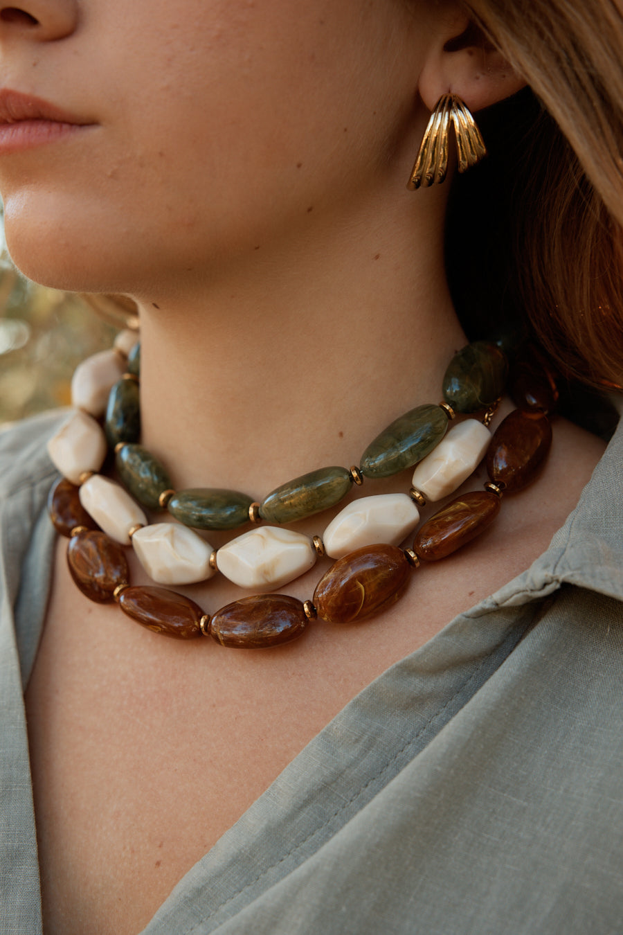 Cou d’une femme portant 3 colliers en résine 