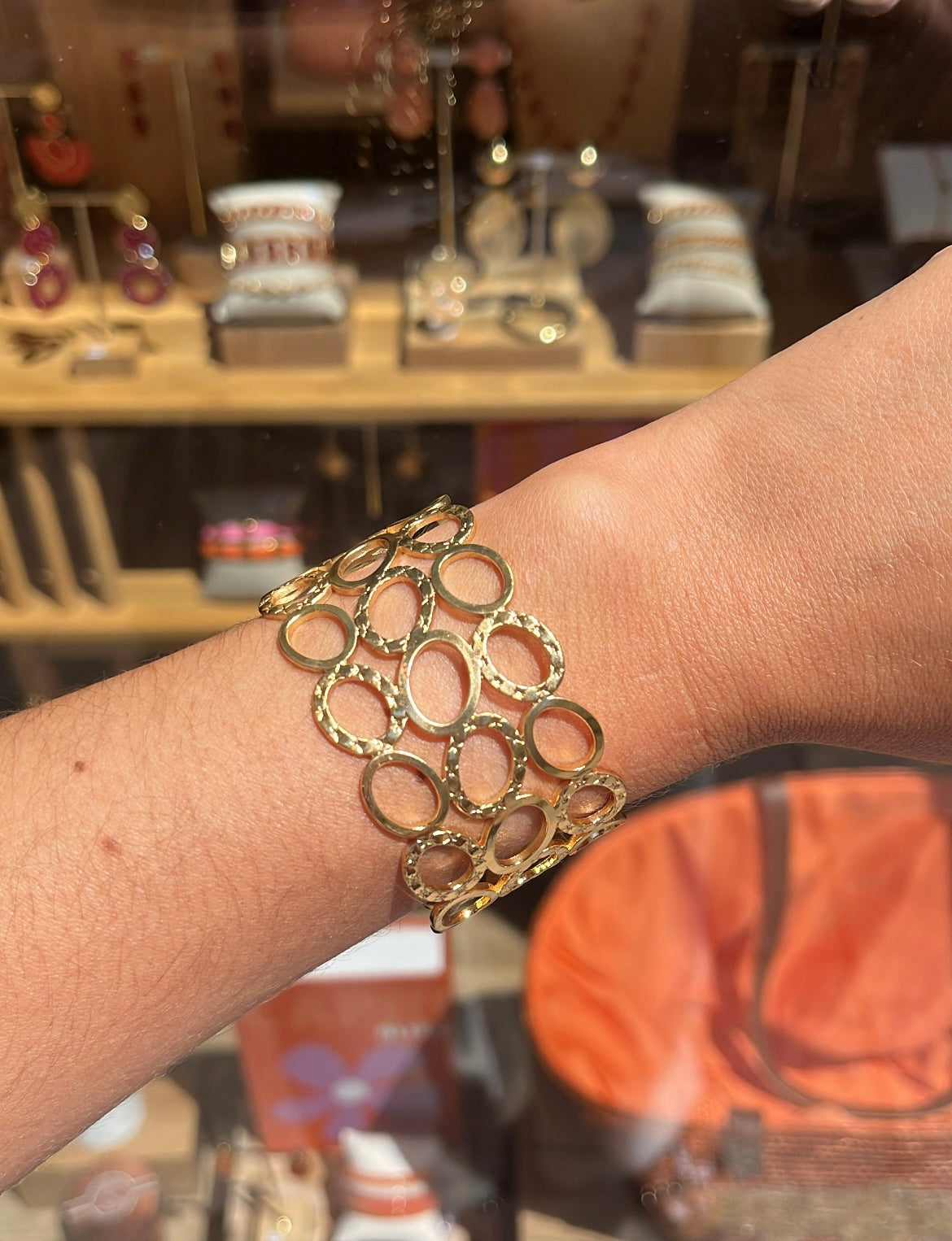 Poignet de femme portant une manchette Avec des cercles ajourés en acier inoxydable doré 