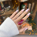 Main de femme portant une bague en acier inoxydable doré, serti d une pierre ovale rouge en résine 