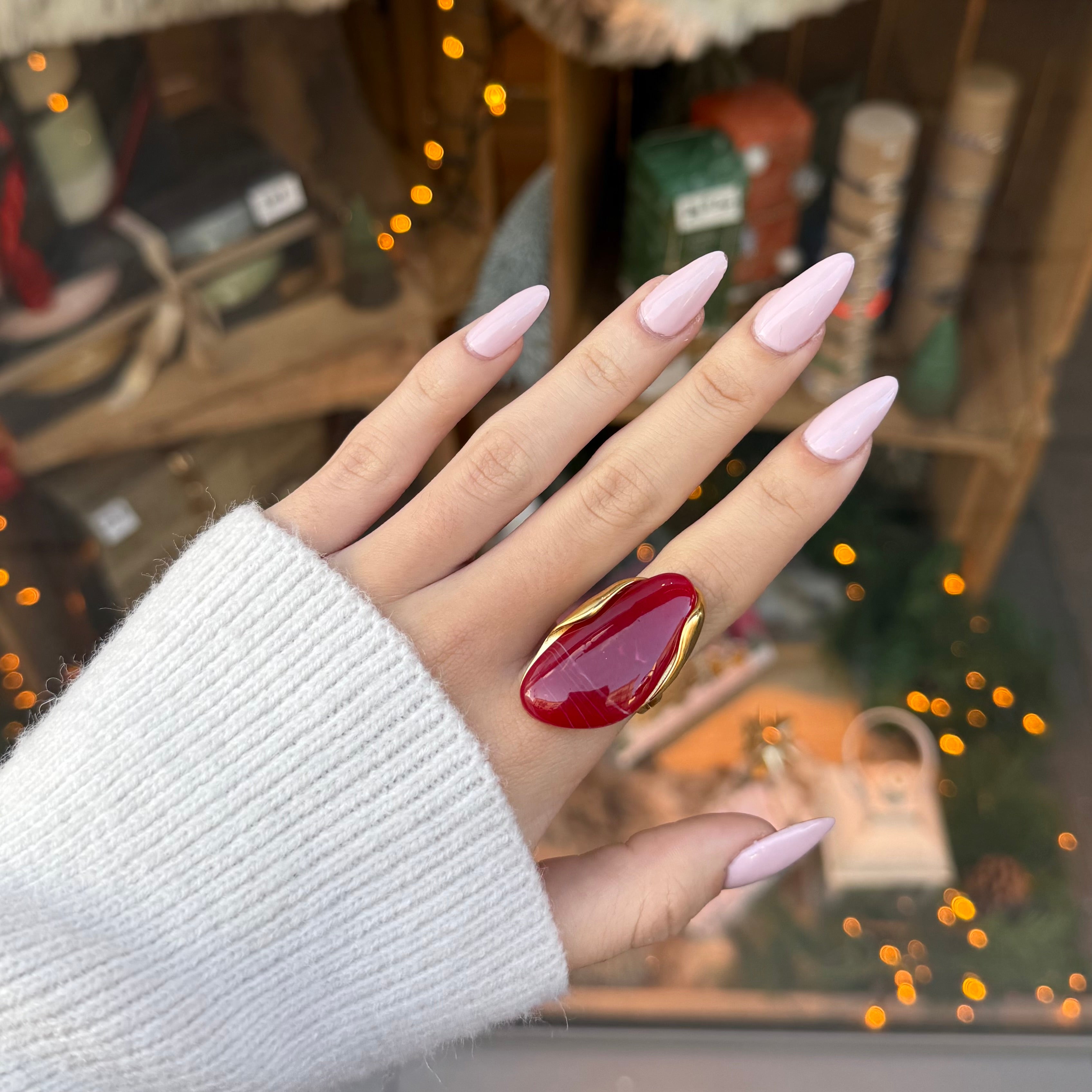 Main de femme portant une bague en acier inoxydable doré, serti d une pierre ovale rouge en résine 