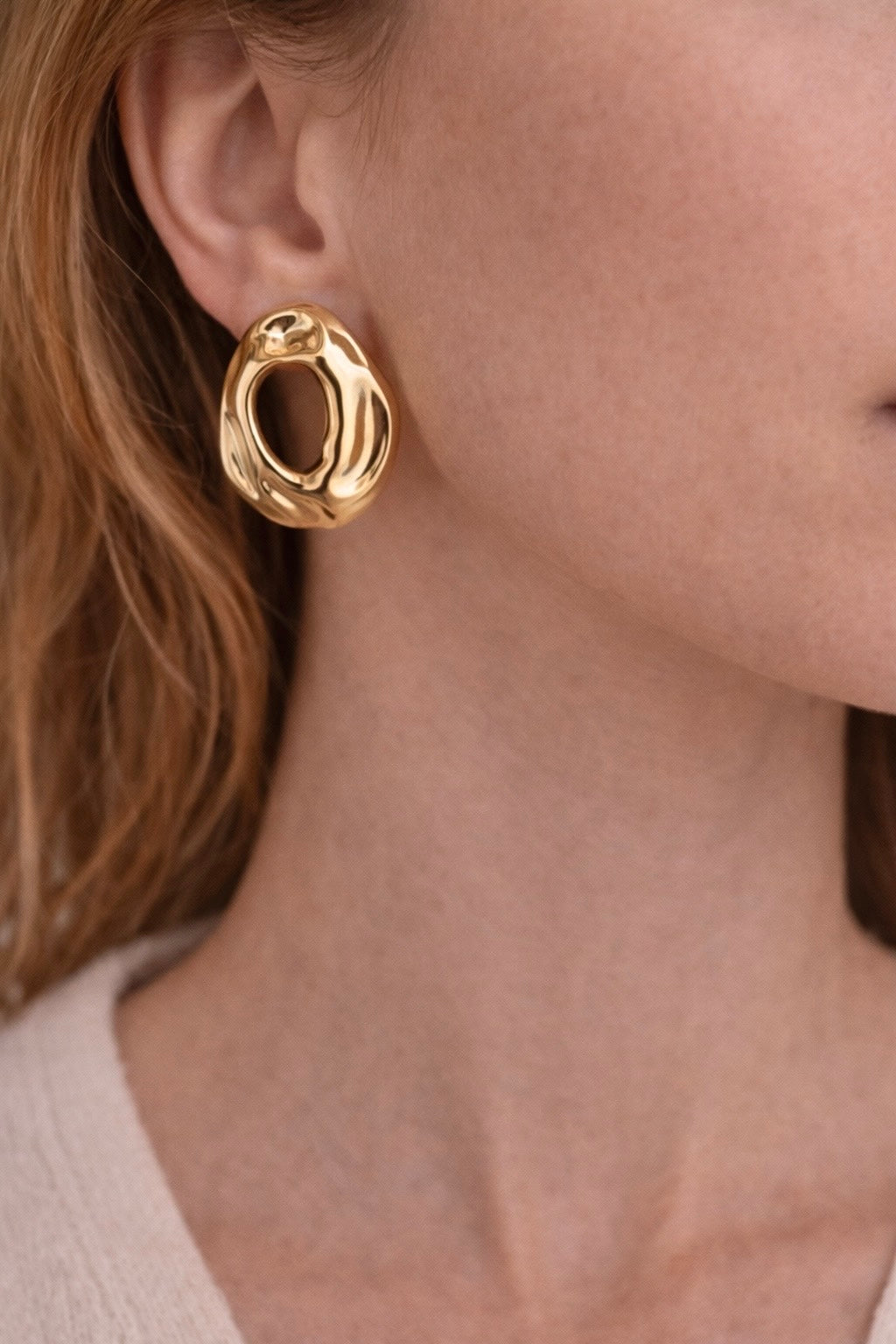 Femme qui porte une paire de boucles d oreilles en acier inoxydable doré, cercle ajouré au milieu de la boucles 