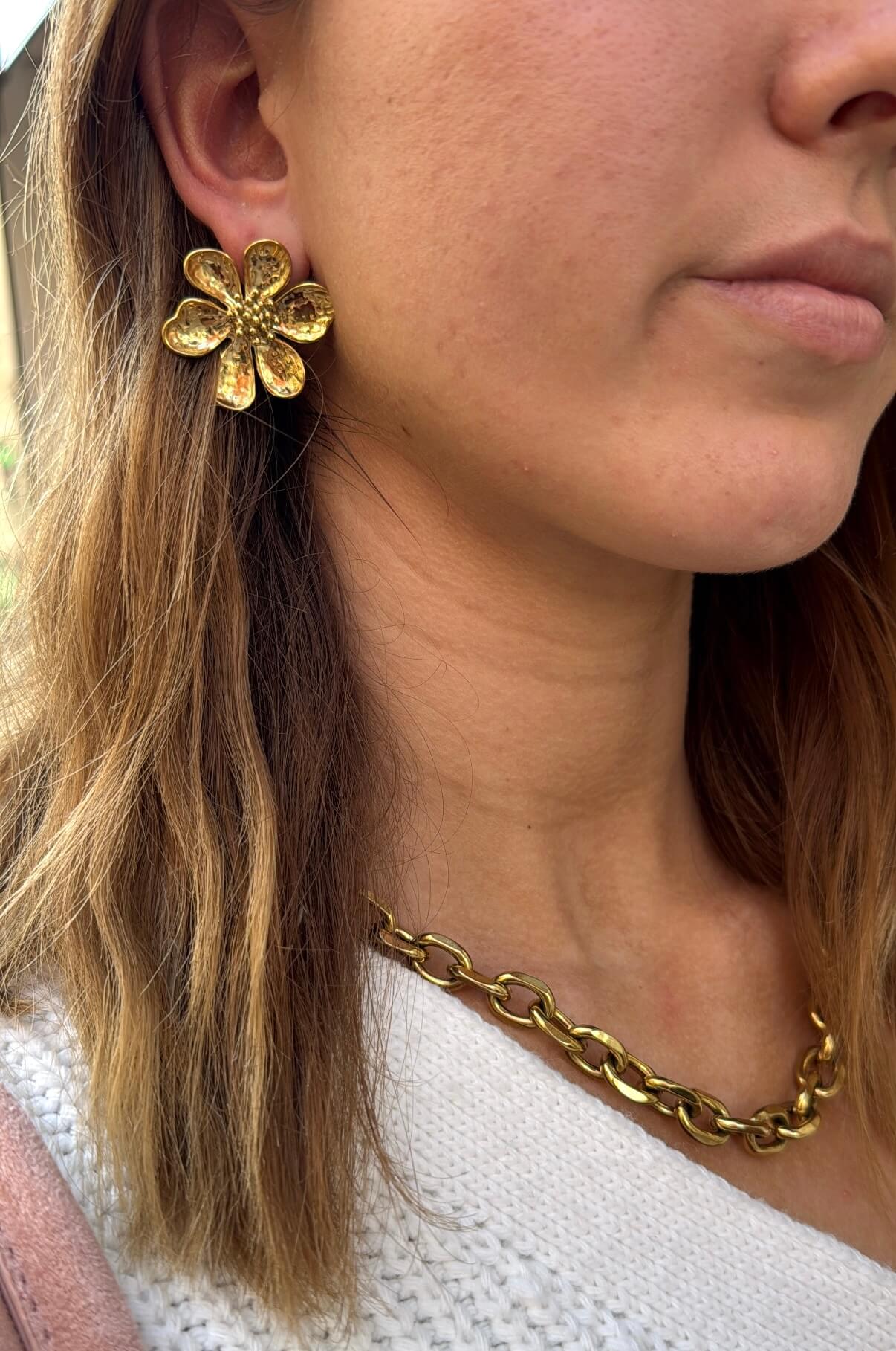 Femme portant une paire de boucles d’oreilles en forme de fleur en acier inoxydable doré