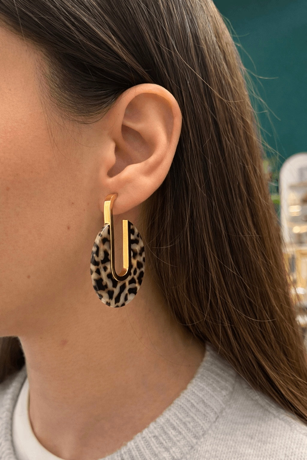 Femme portant une paire de boucles d oreilles pendante en acier inoxydable doré et résine avec des motifs léopard 