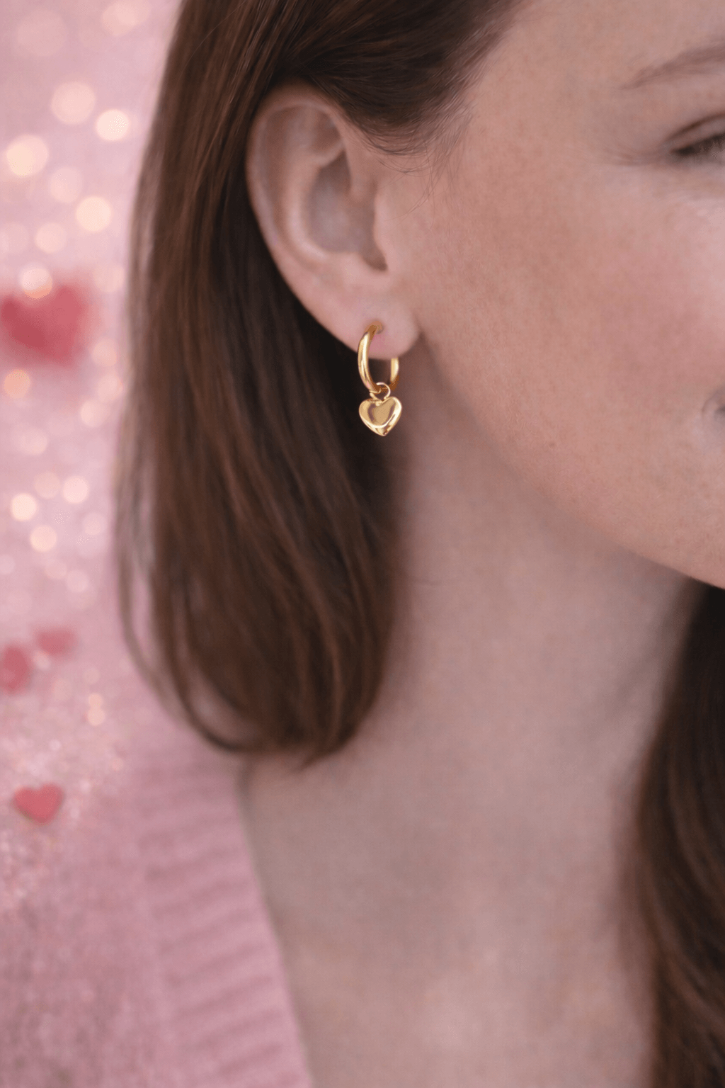 Boucles d’oreilles style créoles avec des coeurs, en acier inoxydable doré, portées par une femme 