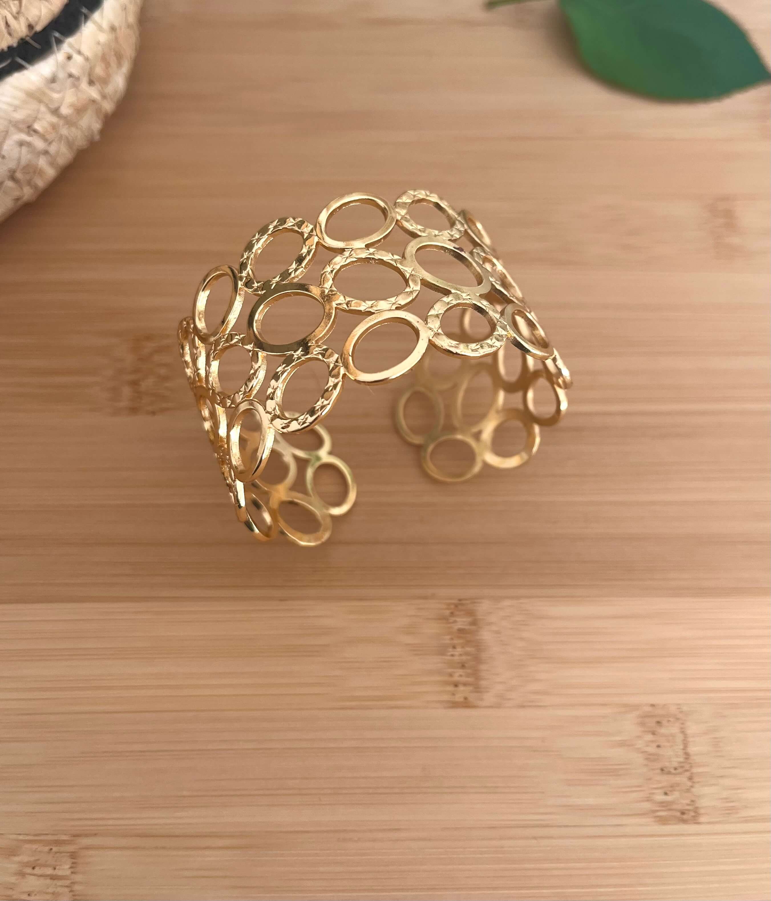 Bracelet manchette avec plein de trous ajourés, dont certains martelé, en acier inoxydable doré 