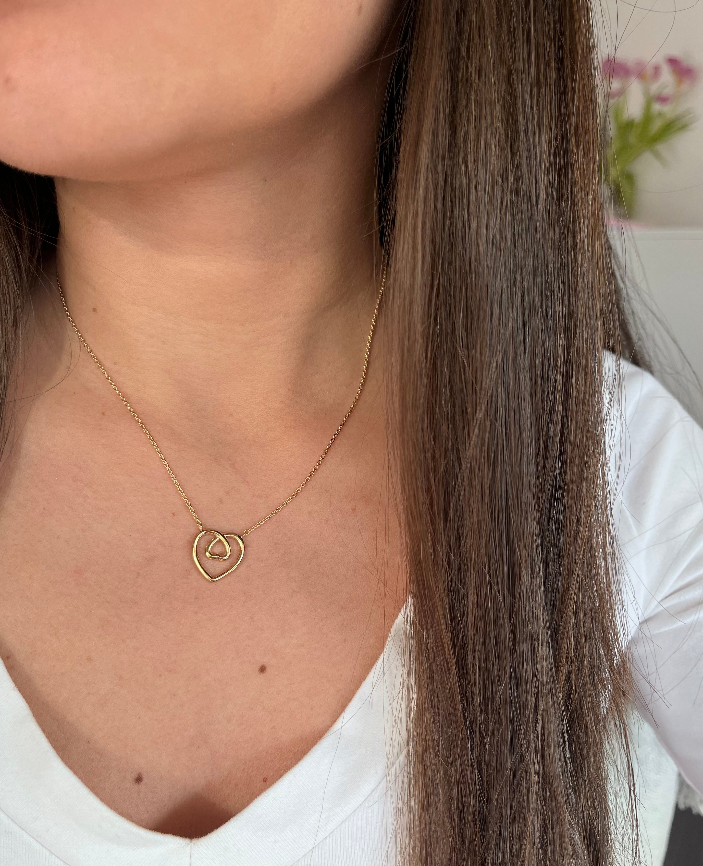 Cou d une femme portant un collier coeur entrelacé en plaqué or 