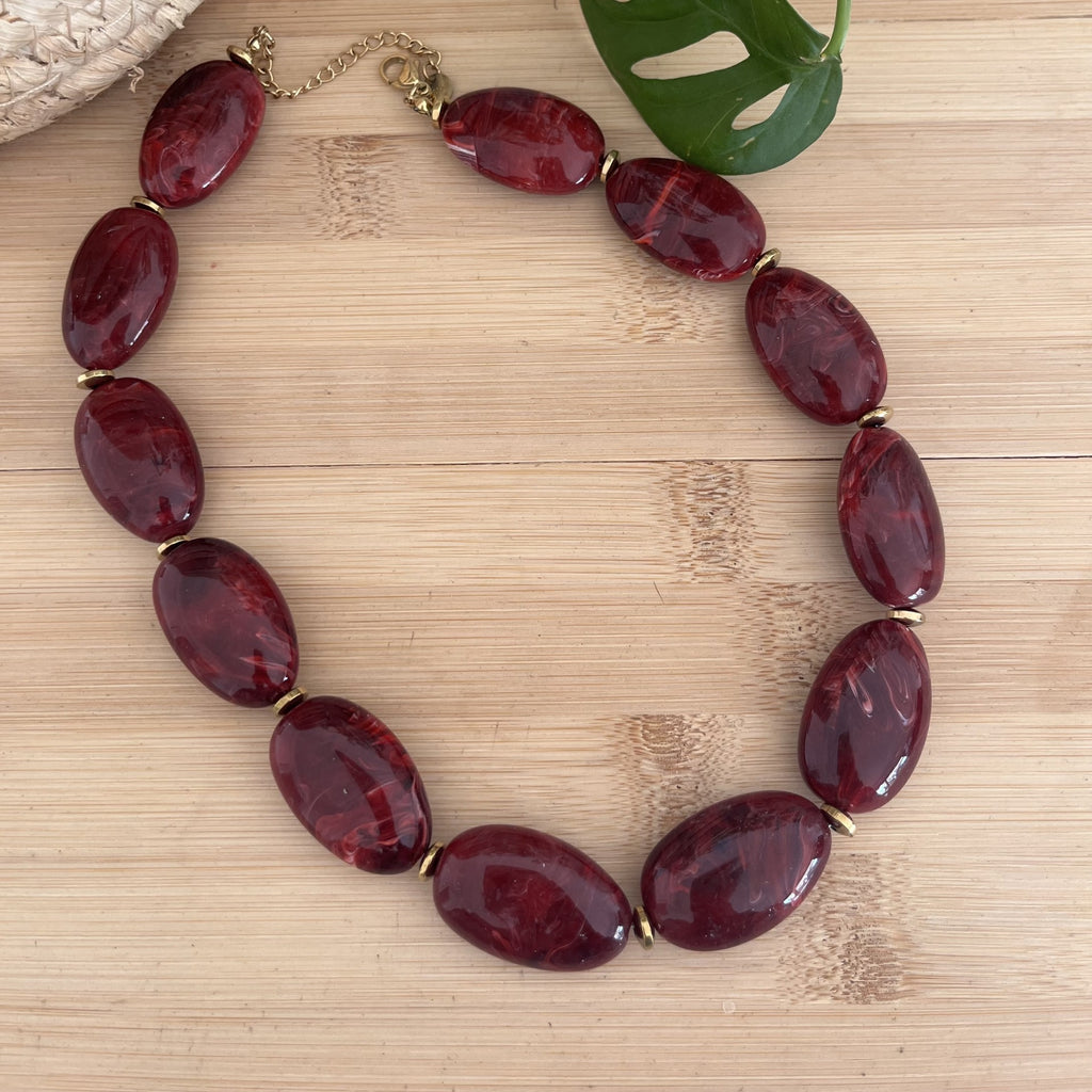 Collier femme a perle ovale en résine bordeaux, avec des perles en acier inoxydable doré en guise de séparateur 