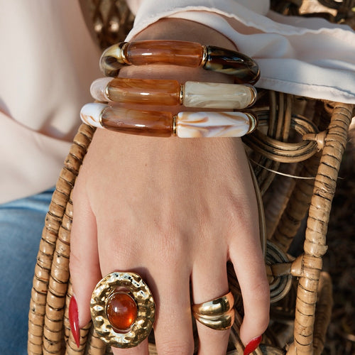 Avant bras d’une femme portant des bracelets en résine, et 2 bagues en acier inoxydable doré