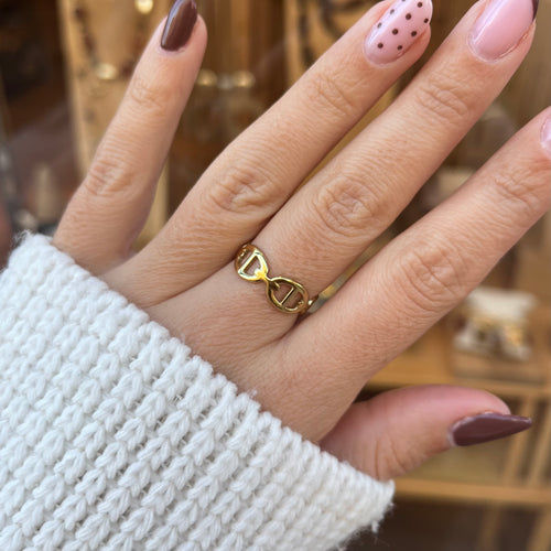 Main de femme portant une bague dorée en acier inoxydable, fine en maille marine