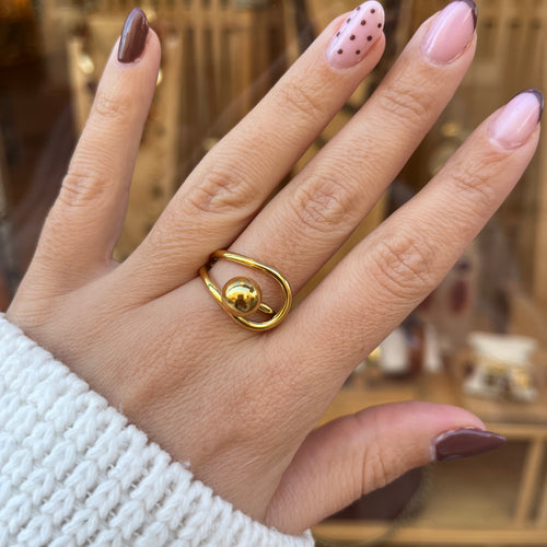 Main de femme portant une bague en acier inoxydable doré, réglable, avec une boucle pris dans un anneau 