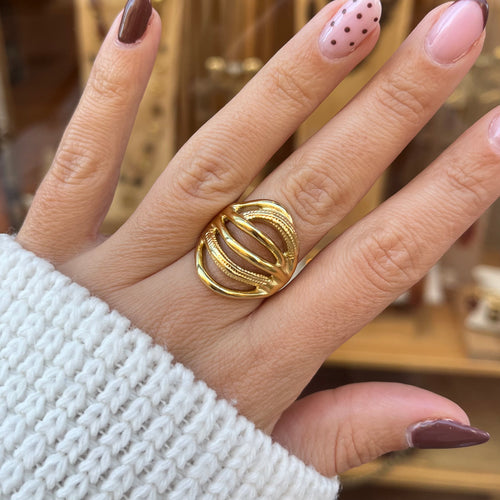 Main portant une bague en acier inoxydable doré avec des traits lisse et d’autres en relief 