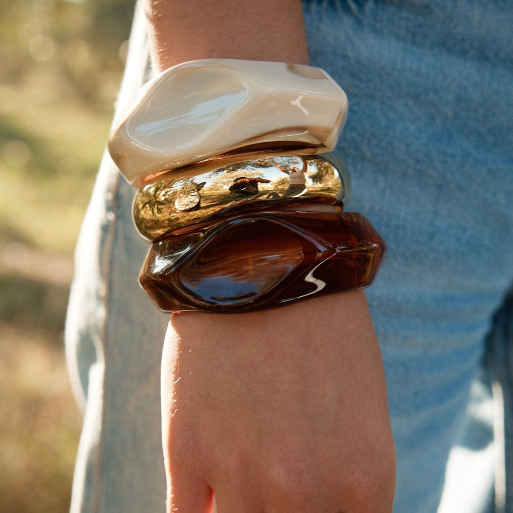 Poignet de femme portant 3 bracelets joncs donc 2 en résine et 1 en acier inoxydable