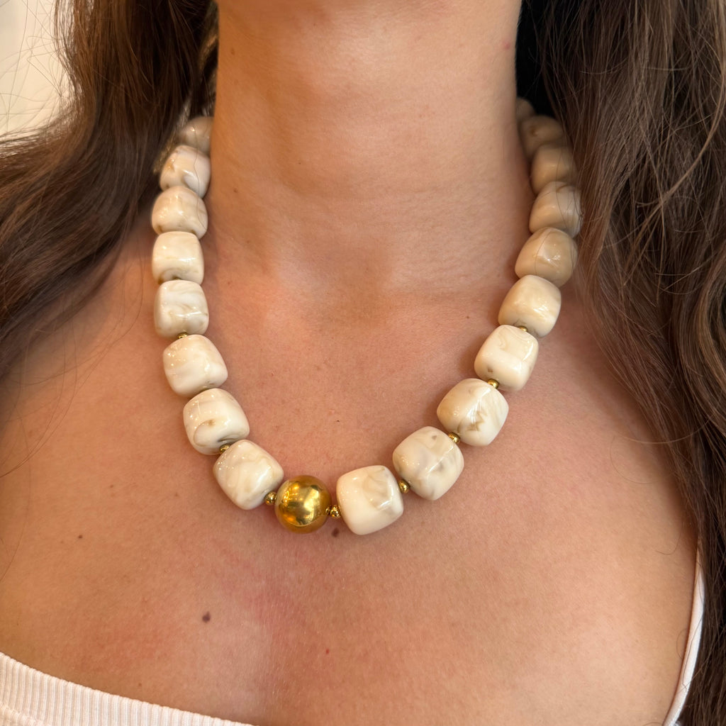 Collier en perle de résine blanc cassé porté par une femme