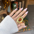 Main de femme portant une bague en acier inoxydable doré, style martelé a ce une pierre ovale marron sur le dessus