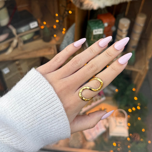 Main d’une femme portant une bague réglable en acier inoxydable doré en forme de S