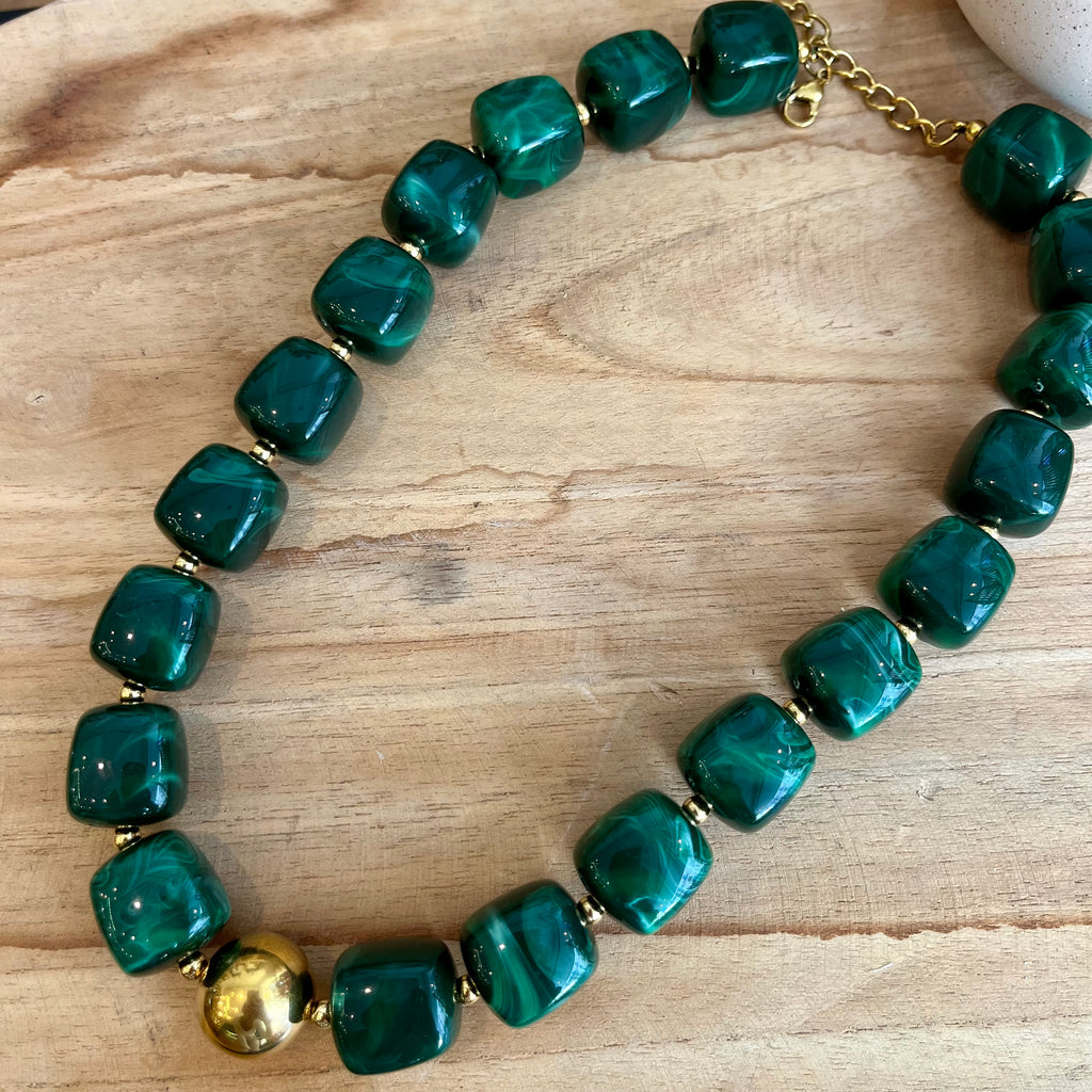 Collier femme avec des perles carrées en résine de couleur verte, ainsi qu’une perle en acier inoxydable doré au centre 