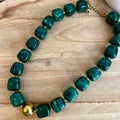 Collier femme avec des perles carrées en résine de couleur verte, ainsi qu’une perle en acier inoxydable doré au centre 