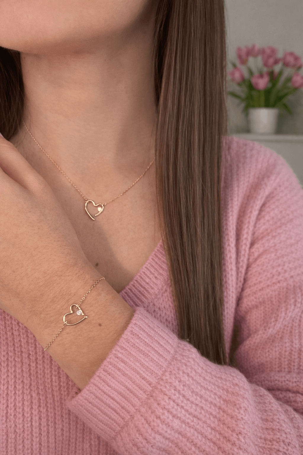 Femme portant une parure de bijoux, comprenant un collier et un bracelet coeur en plaqué or