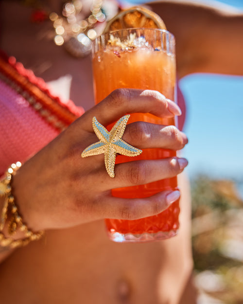 main d'une femme portant une bague en forme d'étoile de mer en acier inoxydable doré