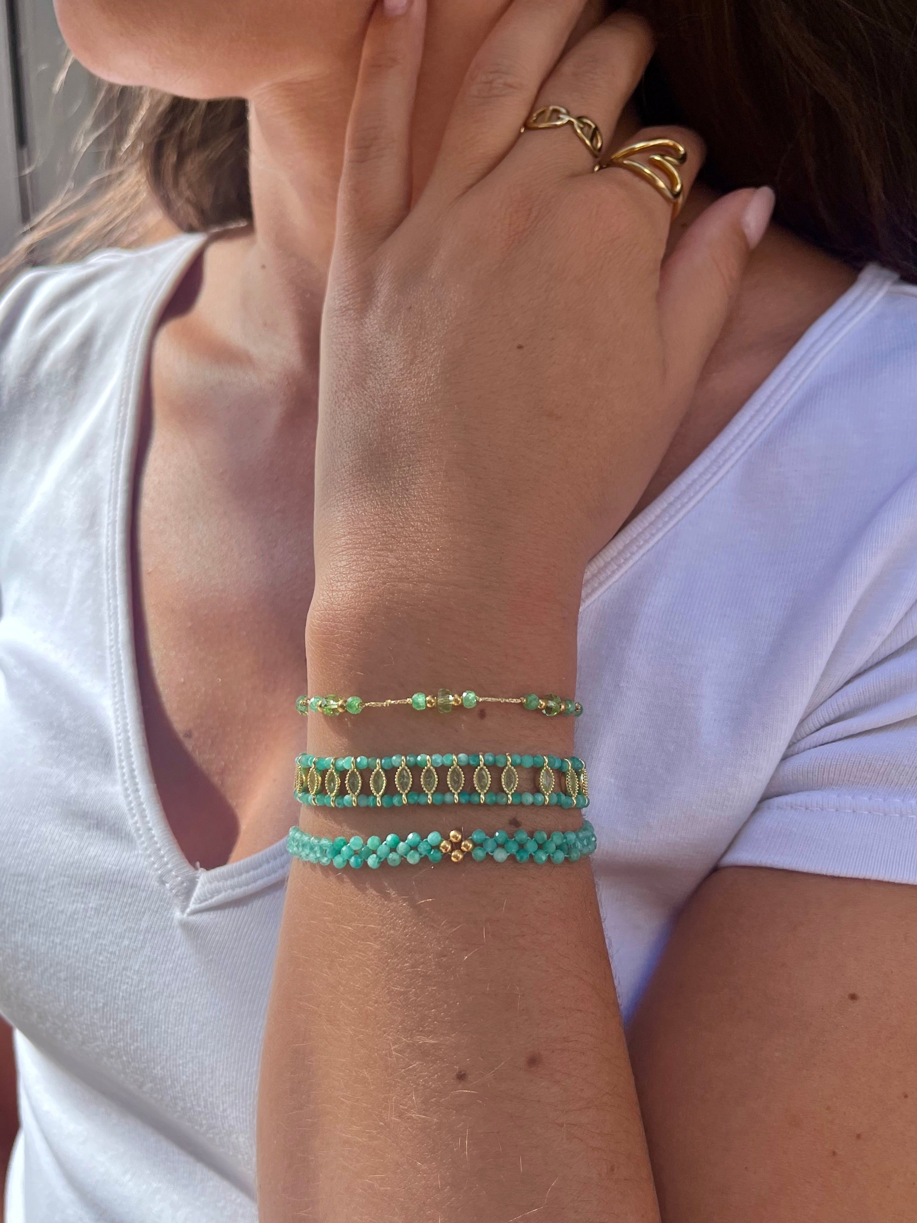 poignet de femme portant trois bracelets de couleurs turquoise, en acier inoxydable doré et en pierres naturelles