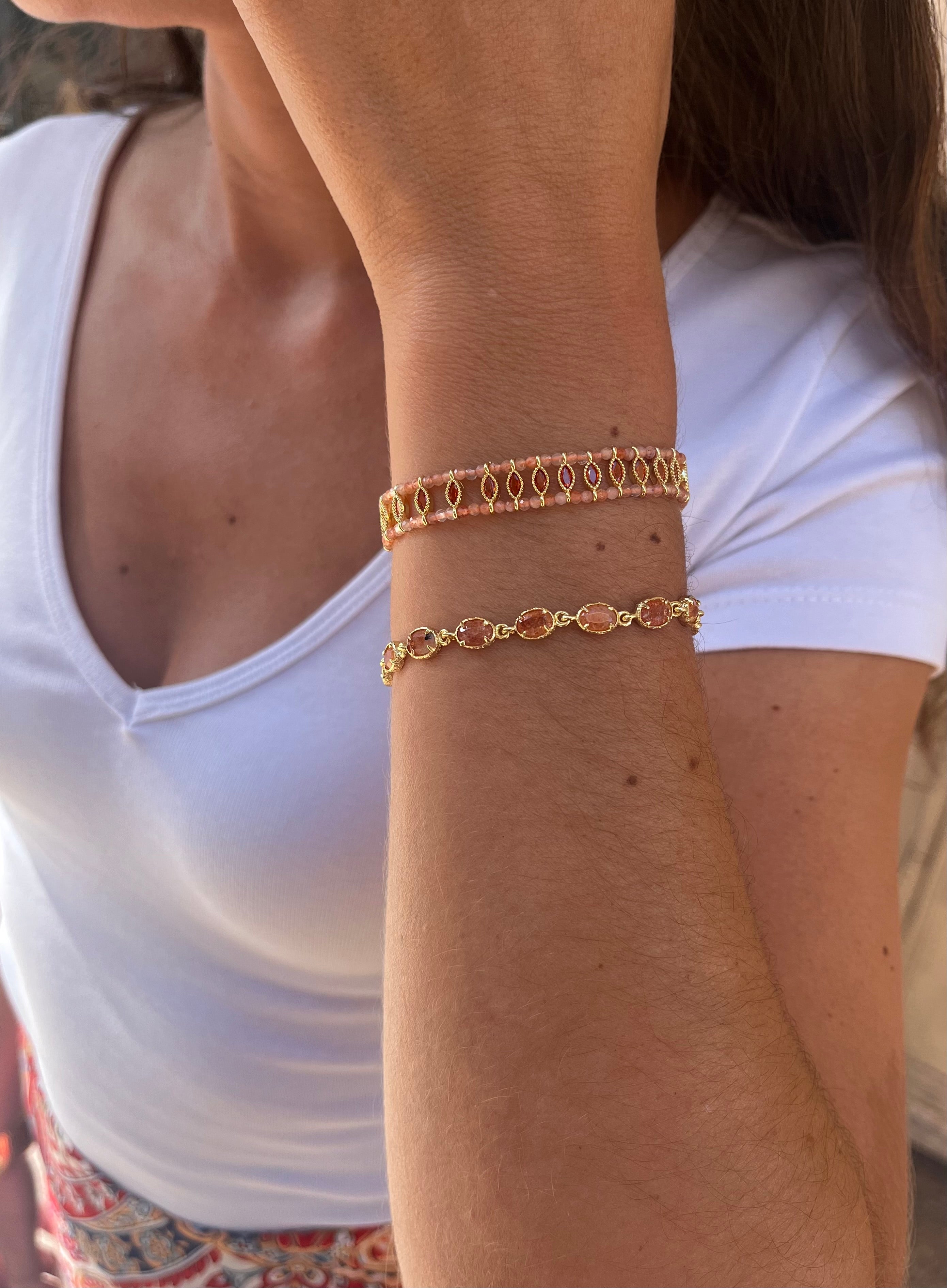 poignet d'une femme portant deux bracelets en pierres naturelles orange en cornaline et acier inoxydable