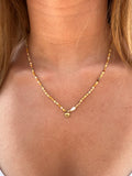cou d'une femme portant un collier de pierres naturelles jaune avec un petit coeur en acier inoxydable doré et une perle blanche