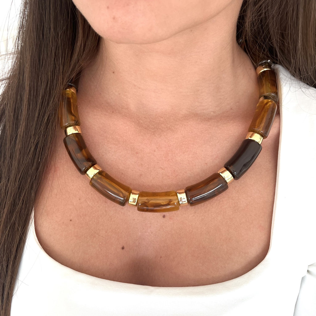 Cou d’une femme portant un collier en résine marron et acier inoxydable doré