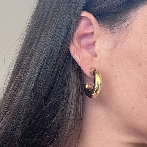 Femme portant une paire de boucles d’oreilles créole en acier inoxydable doré