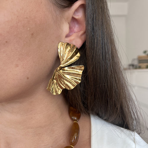 Paire de boucles d’oreilles en demie fleur, aspect martelé, résistant à l’eau, porté par une femme